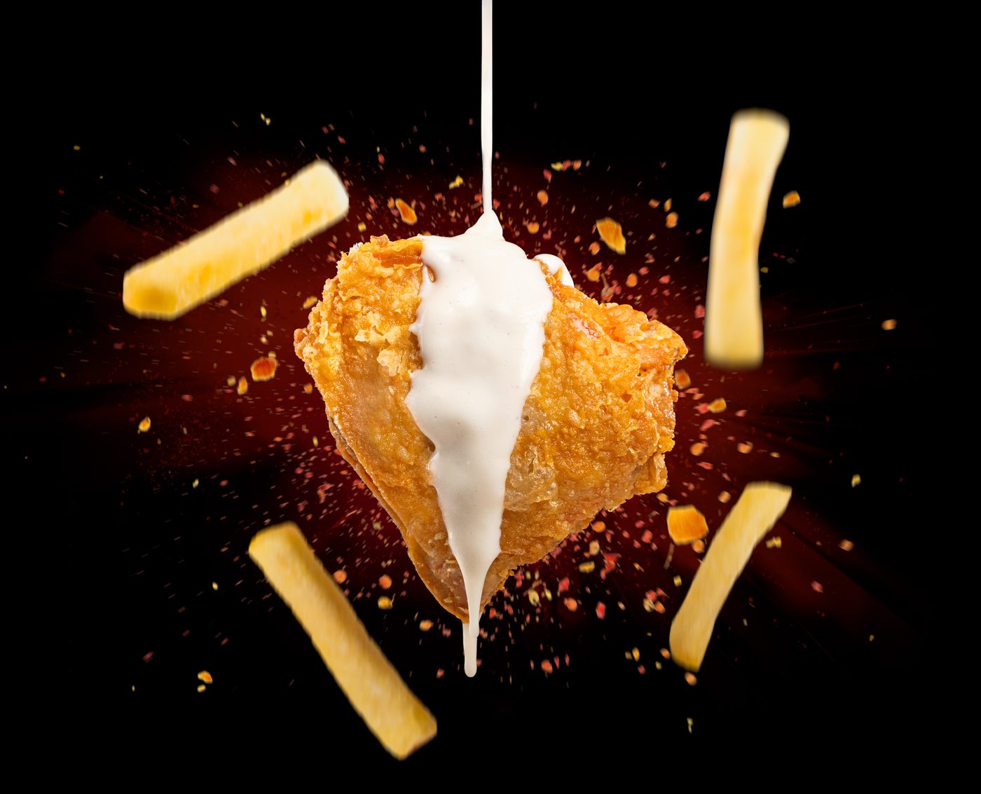 Broast and fries flying with garlic sauce on a dark background
