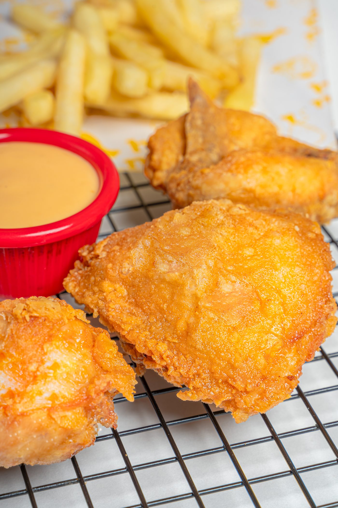 A crispy piece of hen n' bun spicy broast with a dip
