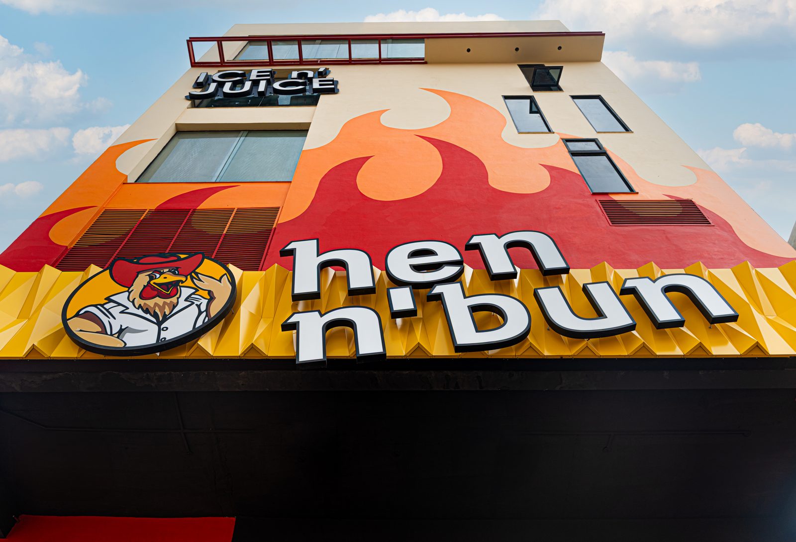 The hen n' bun rooster logo and sign on a branch building